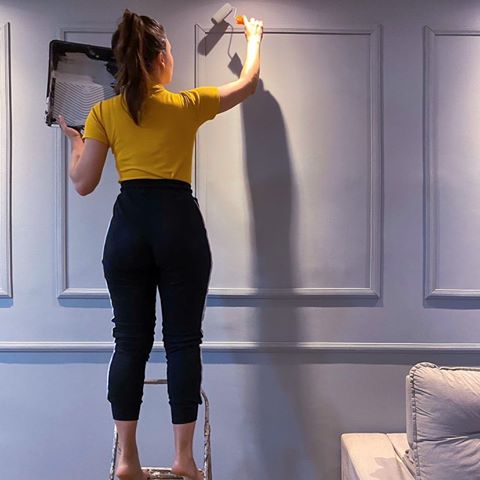 Fotografia de mulher pintando parede com boiserie autocolante